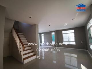 Spacious living room with staircase and large windows