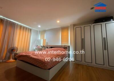 Spacious bedroom with wooden flooring, large bed, and ample storage