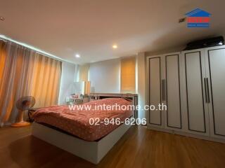 Spacious bedroom with wooden flooring, large bed, and ample storage