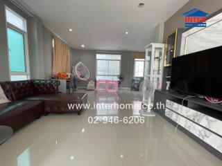 Spacious living room with leather sofa, TV, and large windows