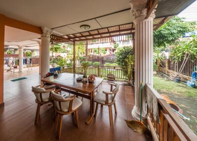 Covered patio with dining table overlooking a garden