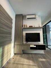 Modern living room with air conditioner, wall-mounted TV, and sliding glass door