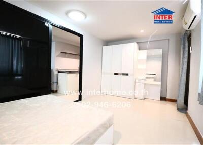 Spacious bedroom with bed, wardrobe, and adjoining kitchen
