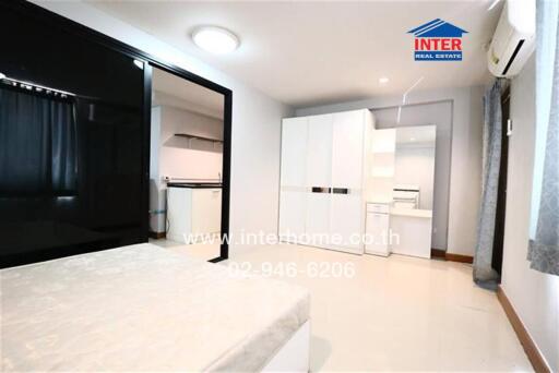 Spacious bedroom with bed, wardrobe, and adjoining kitchen