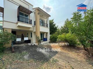 Two-story house with overgrown foliage and a paved driveway under clear skies