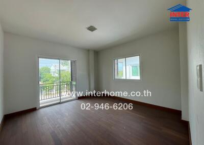 Empty bedroom with wooden flooring and small balcony