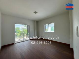 Empty bedroom with wooden flooring and small balcony