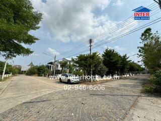 Street view of a neighborhood with houses, trees, and a car on the road