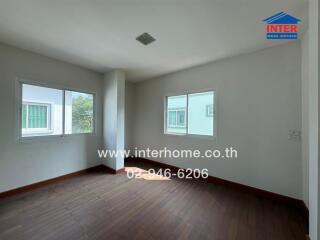 Residential bedroom with hardwood floors and two windows