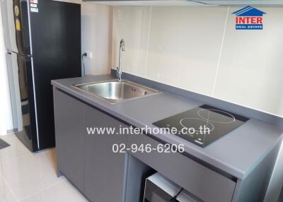 Modern kitchen with a black refrigerator, induction stove, and stainless steel sink