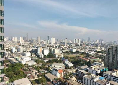 Panoramic view of a city skyline with numerous buildings under a partly cloudy sky