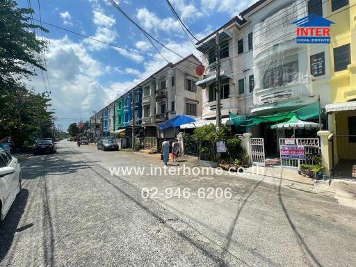 Street view of residential buildings with real estate signs