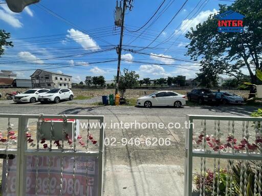 View from the entrance of a residential property showing cars parked outside and a clear sky