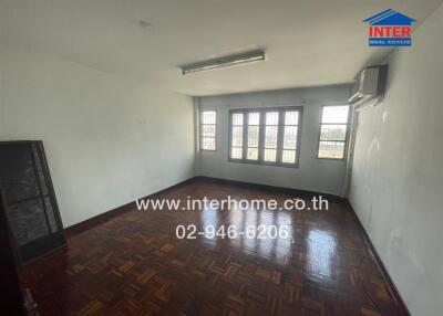 Empty living room with polished wooden floor and large windows