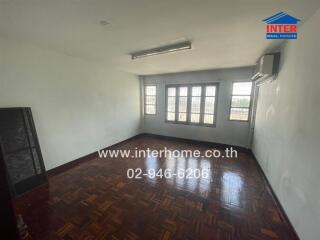 Empty living room with polished wooden floor and large windows