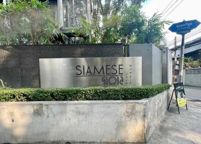 Entrance of Siamese Gioia building with sign and surrounding greenery