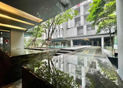 Modern residential building with reflective water feature and landscaped greenery