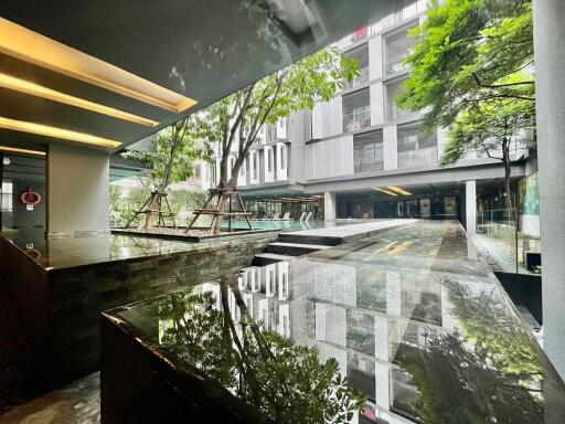 Modern residential building with reflective water feature and landscaped greenery