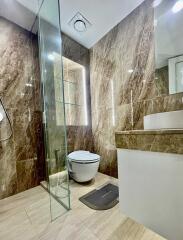 Modern bathroom with glass shower partition and marble walls