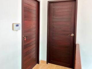 Hallway with dark wooden doors and security panel