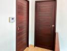 Hallway with dark wooden doors and security panel