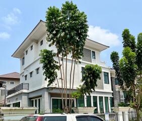 Modern multi-story residential building with a white facade and green accents