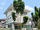 Modern multi-story residential building with a white facade and green accents