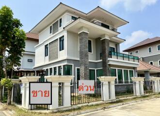 Exterior view of a modern multi-story house with large windows and a fenced yard