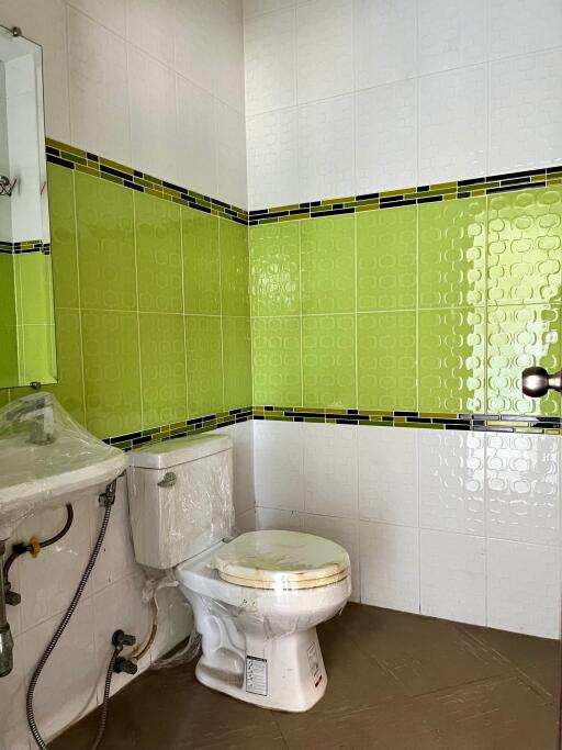 Bathroom featuring white and green tiles with a sink and toilet.