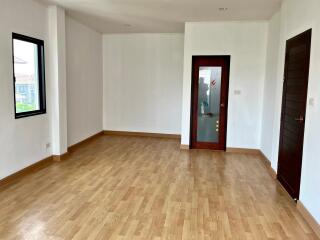 Spacious empty living room with wooden floor and large windows