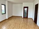 Spacious empty living room with wooden floor and large windows