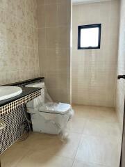 A bathroom with tiled walls, a window, a sink with vanity, and a toilet.