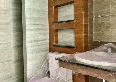 Modern bathroom with wooden accents and sanitary fixtures wrapped in plastic