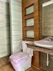 Modern bathroom with wooden accents and sanitary fixtures wrapped in plastic