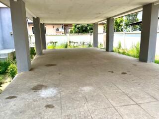 Covered parking area with tiled floor and supporting pillars