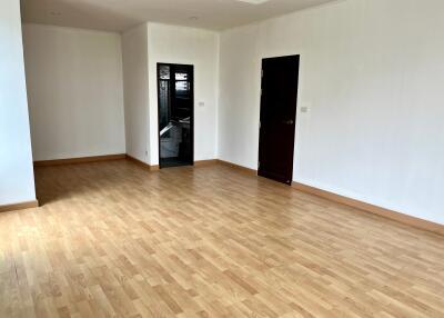 Spacious empty room with wooden flooring and two doors