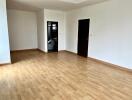 Spacious empty room with wooden flooring and two doors