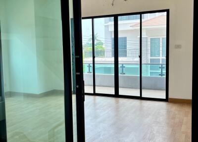 Spacious room with wooden flooring and large glass sliding doors opening to a balcony