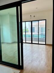 Spacious room with wooden flooring and large glass sliding doors opening to a balcony