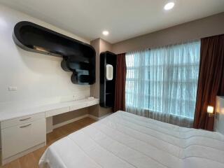 Modern bedroom with white bed, built-in desk, and contemporary shelving