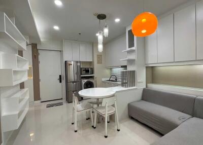 Modern kitchen and living area with white cabinets and grey sofa