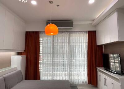Modern living room with large window, air conditioning, and orange pendant light