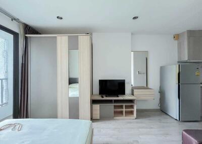 Modern bedroom with wardrobe, TV unit, fridge, and bed