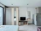 Modern bedroom with wardrobe, TV unit, fridge, and bed