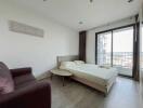 Modern bedroom with a double bed, purple armchair, small round table, balcony, and large window