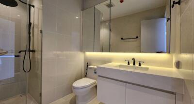 Modern bathroom with glass shower, toilet, and illuminated vanity with mirror