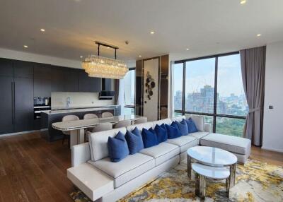 Modern living area with a city view, featuring a plush sofa, dining table, and a contemporary kitchen