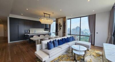 Modern living area with a city view, featuring a plush sofa, dining table, and a contemporary kitchen