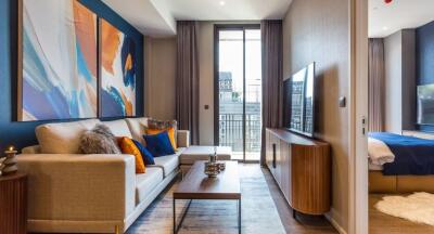 Modern living room with abstract art, a sofa, coffee table, large TV, and access to a bedroom with natural light