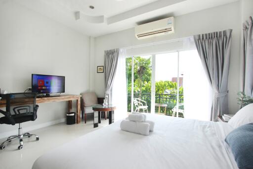 Spacious bedroom with a work desk, views to a balcony with greenery